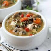 Chicken Wild Rice Soup with carrots and mushrooms with pepper and parsley on a table