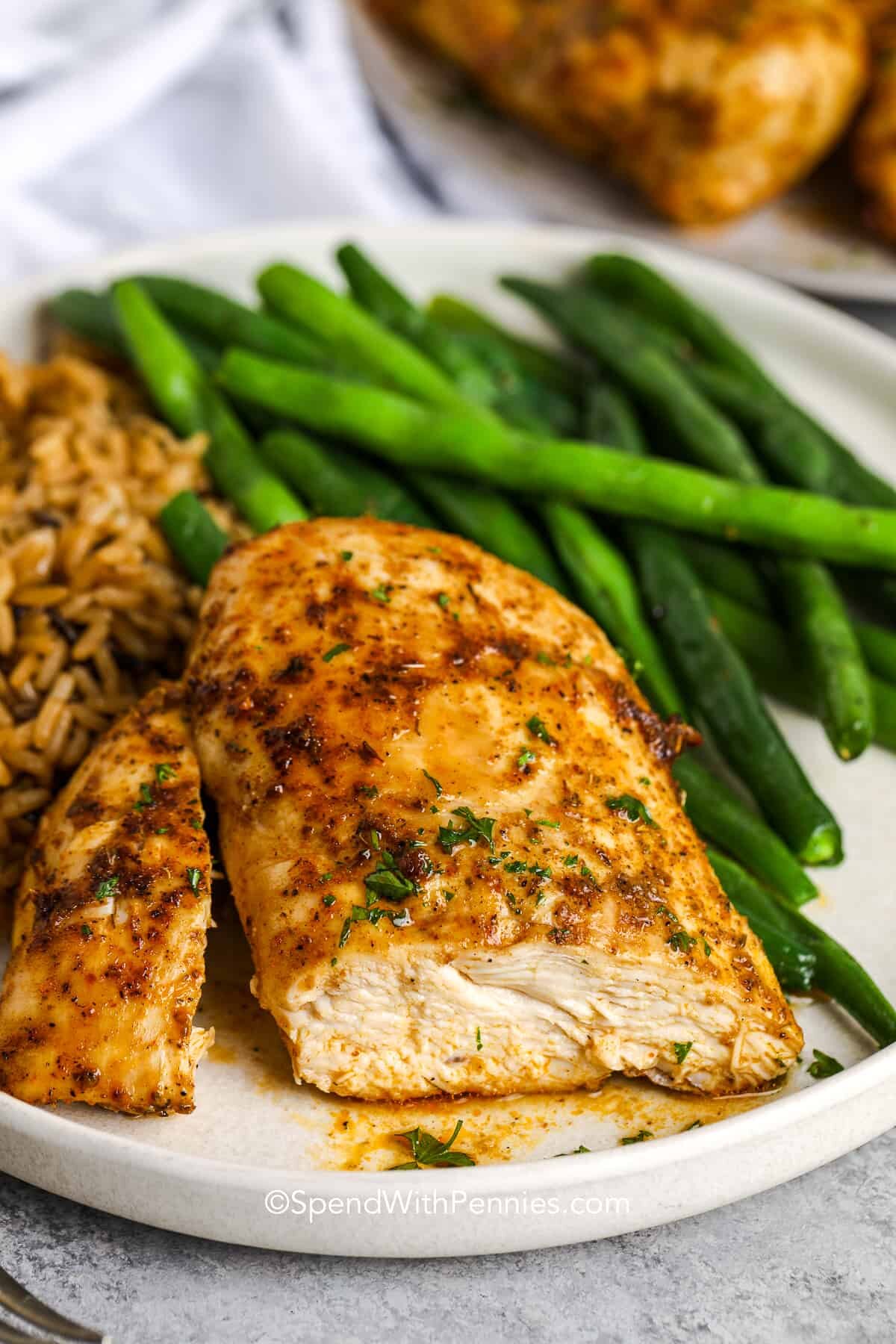 cut air fryer chicken breast with rice and green beans on a plate