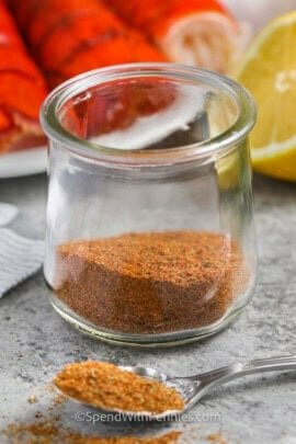 Old Bay Seasoning in a jar with lobster and lemon in the back